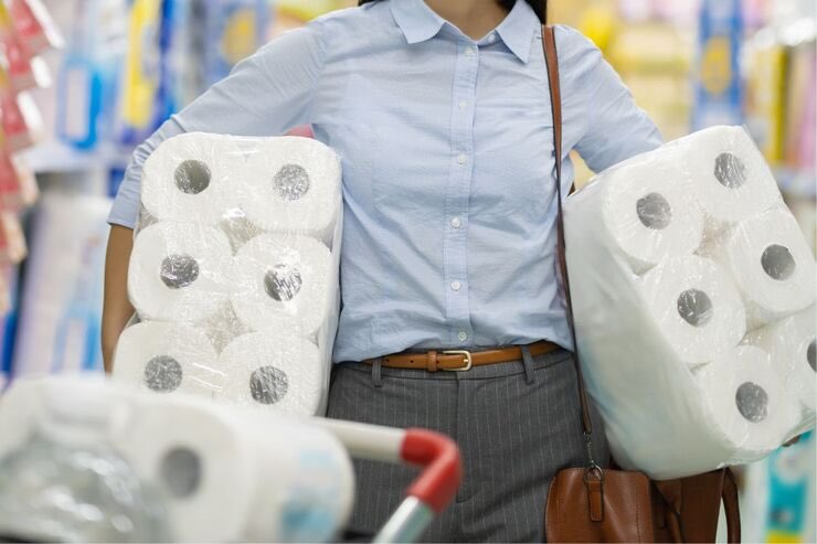 Donna con in mano imballi di carta da cucina assorbente al supermercato