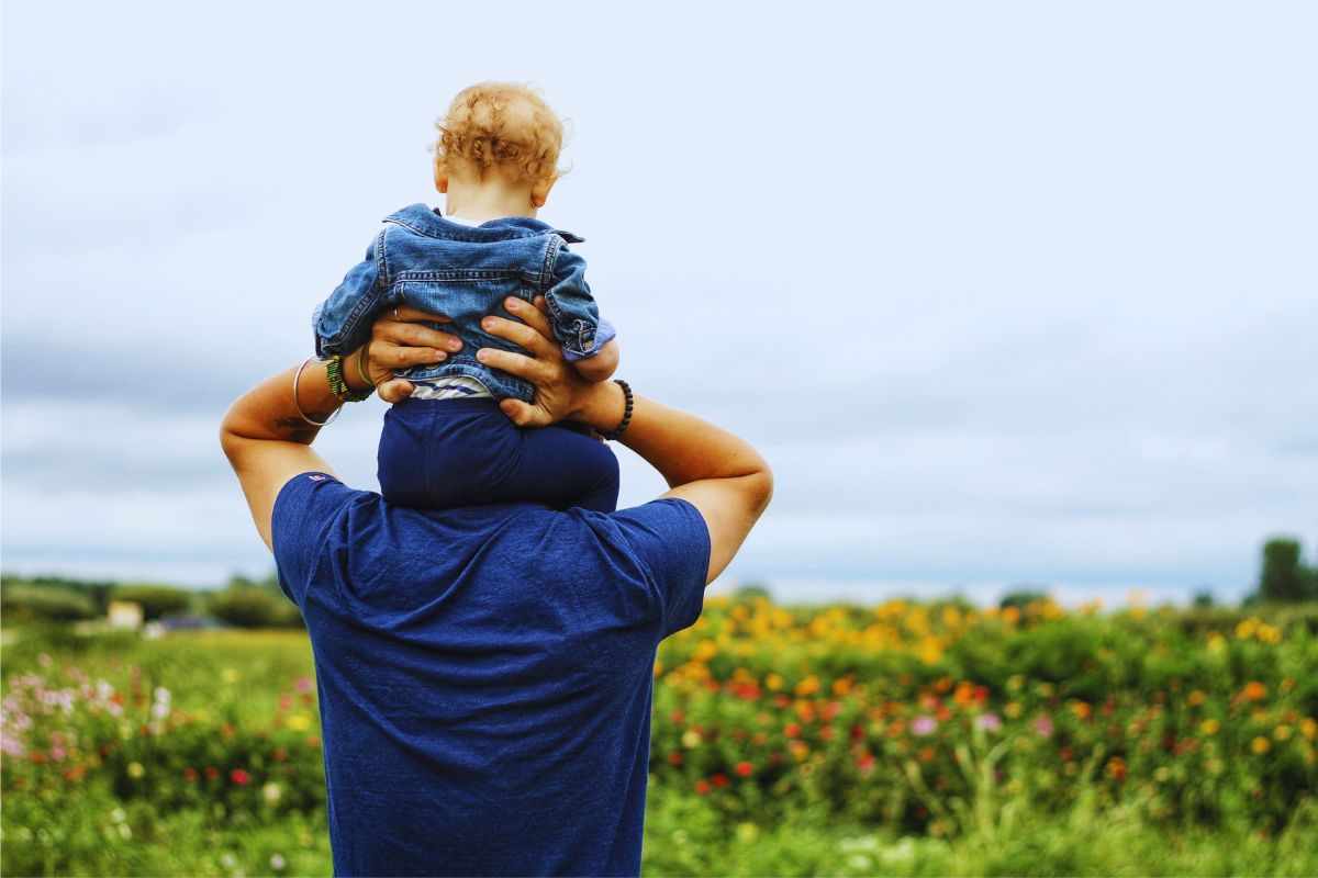 Padre che tiene sulle spalle figlio piccolo