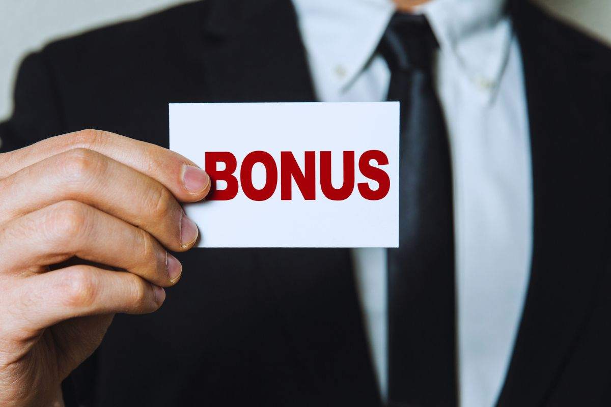 Uomo in abito elegante che tiene un cartellino in cui si legge la scritta "Bonus"