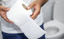uomo in bagno con in mano della carta igienica