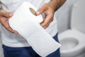 uomo in bagno con in mano della carta igienica