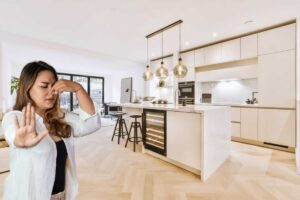Openspace con cucina e sgabelli, donna che si tappa il naso
