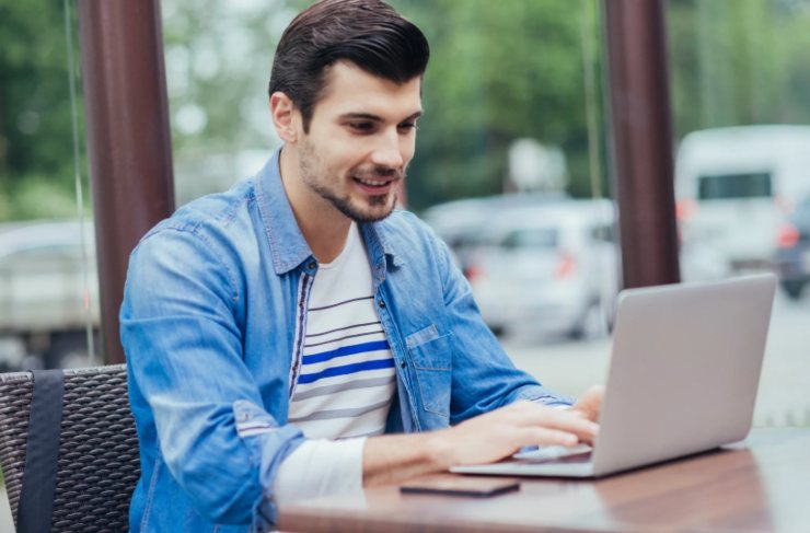 ragazzo che sorride seduto davanti al computer
