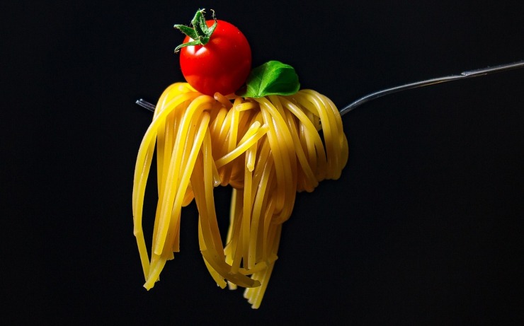 forchettata di spaghetti con sopra un pomodorino rosso