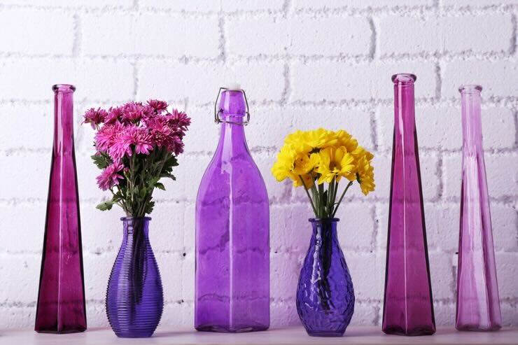 Bottiglie di varie forme e dimensioni di colore viola/fucsia e fiori