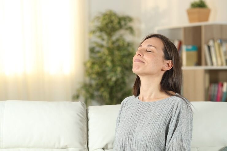Donna seduta sul divano con occhi chiusi si gode relax