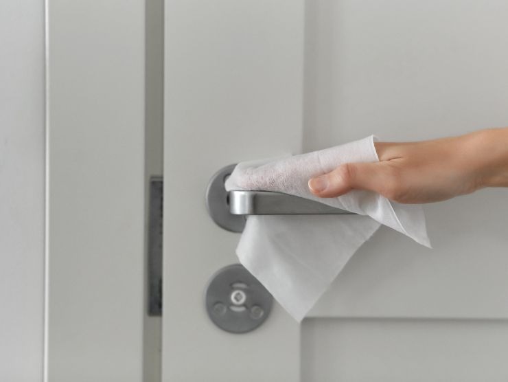 mano che pulisce maniglia della porta