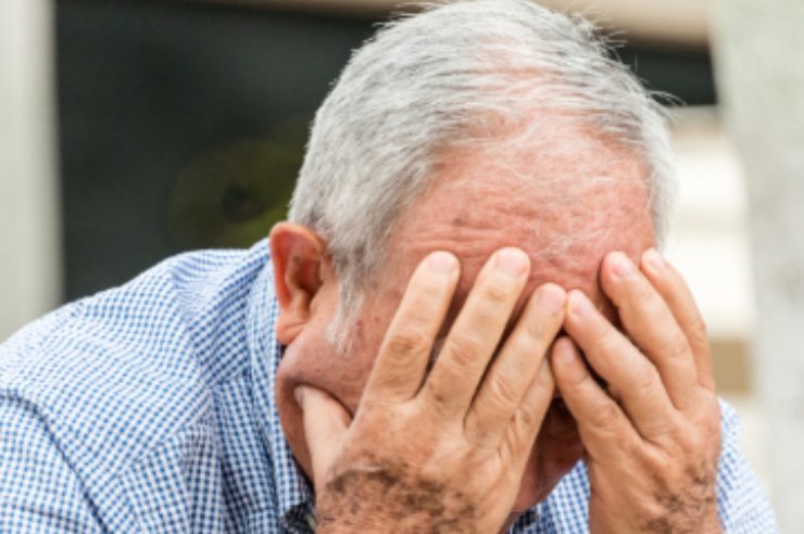 uomo anziano con le mani in faccia