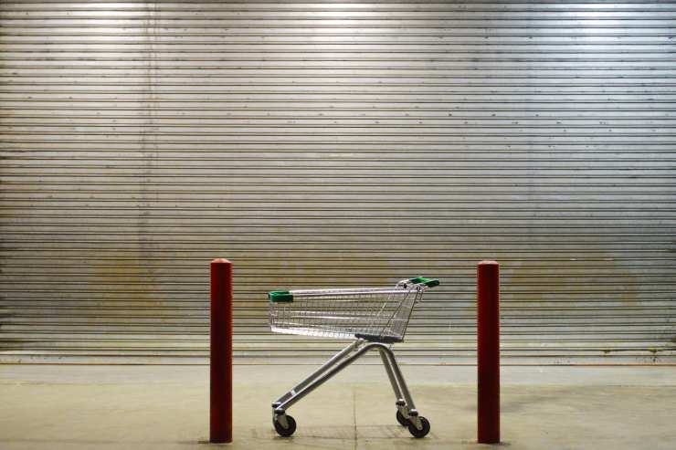 carrello davanti ad una serranda chiusa che rappresenta la chiusura del negozio