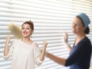donna che pulisce tapparelle e un'altra che esulta