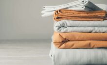 Lenzuola bianche e arancio piegate e impilate