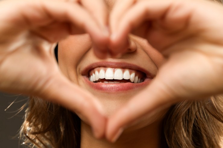 donna che fa il cuore con le mani e all'interno del cuore c'è il suo sorriso
