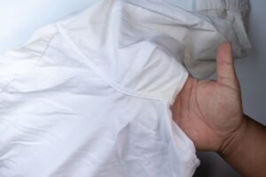 Mano mostra capo bianco con ascelle ingiallite