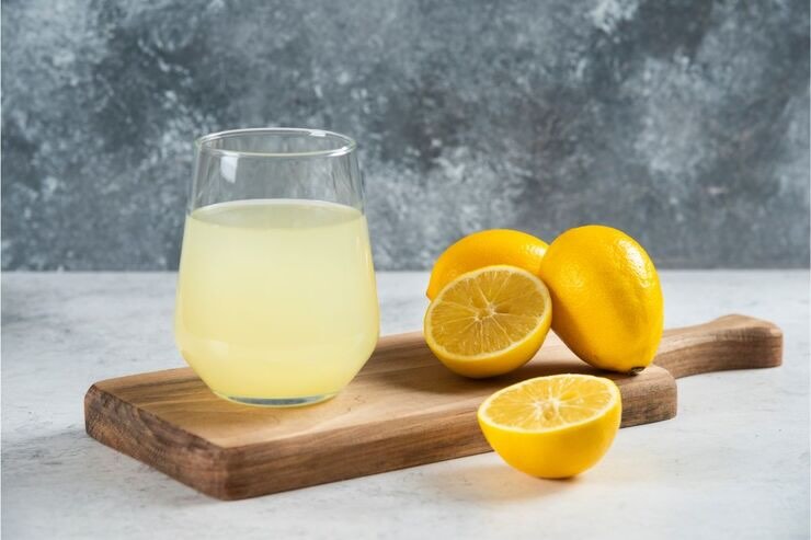 Tagliere con bicchiere di limonata e limoni tagliati